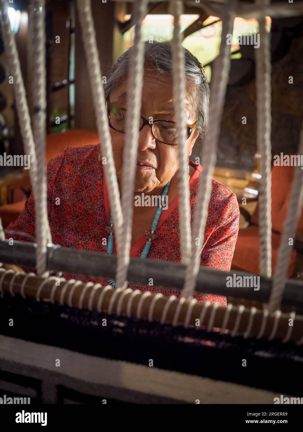 Une femme amérindienne fabrique un tapis dans le hall de l'hôtel El Rancho à Gallup, au Nouveau-Mexique. Photo de Liz Roll Banque D'Images