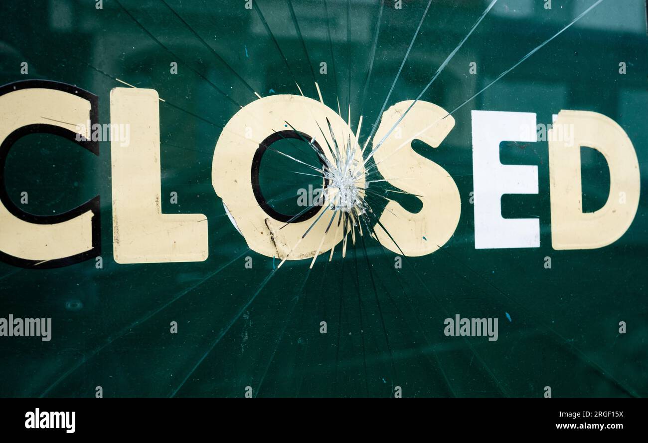 Une affiche indiquant que le magasin est fermé derrière une fenêtre cassée et fissurée Banque D'Images