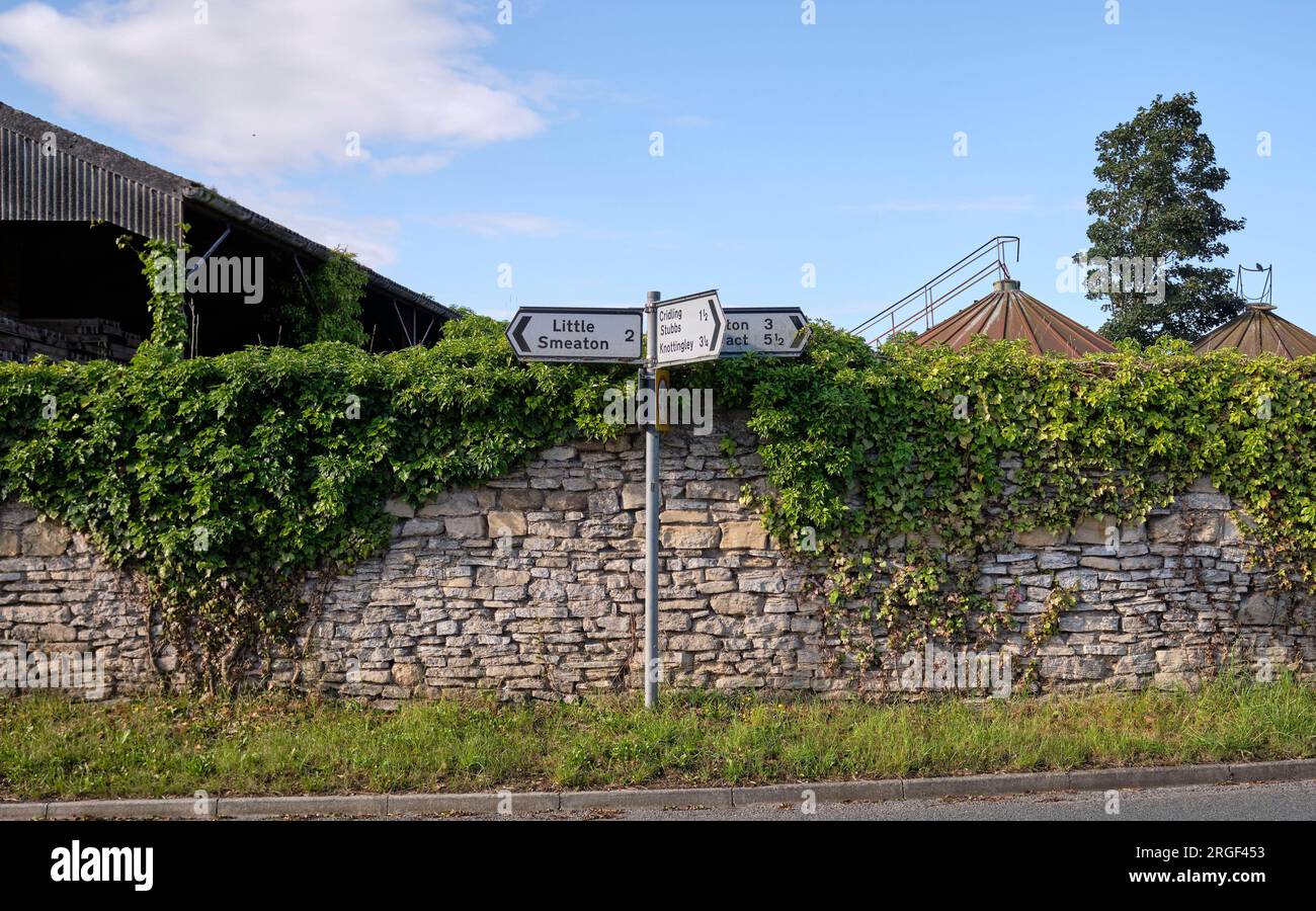 Panneaux de doigts contre un mur de pierre, communauté rurale de Womersley, North Yorkshire, nord de l'Angleterre, Royaume-Uni Banque D'Images