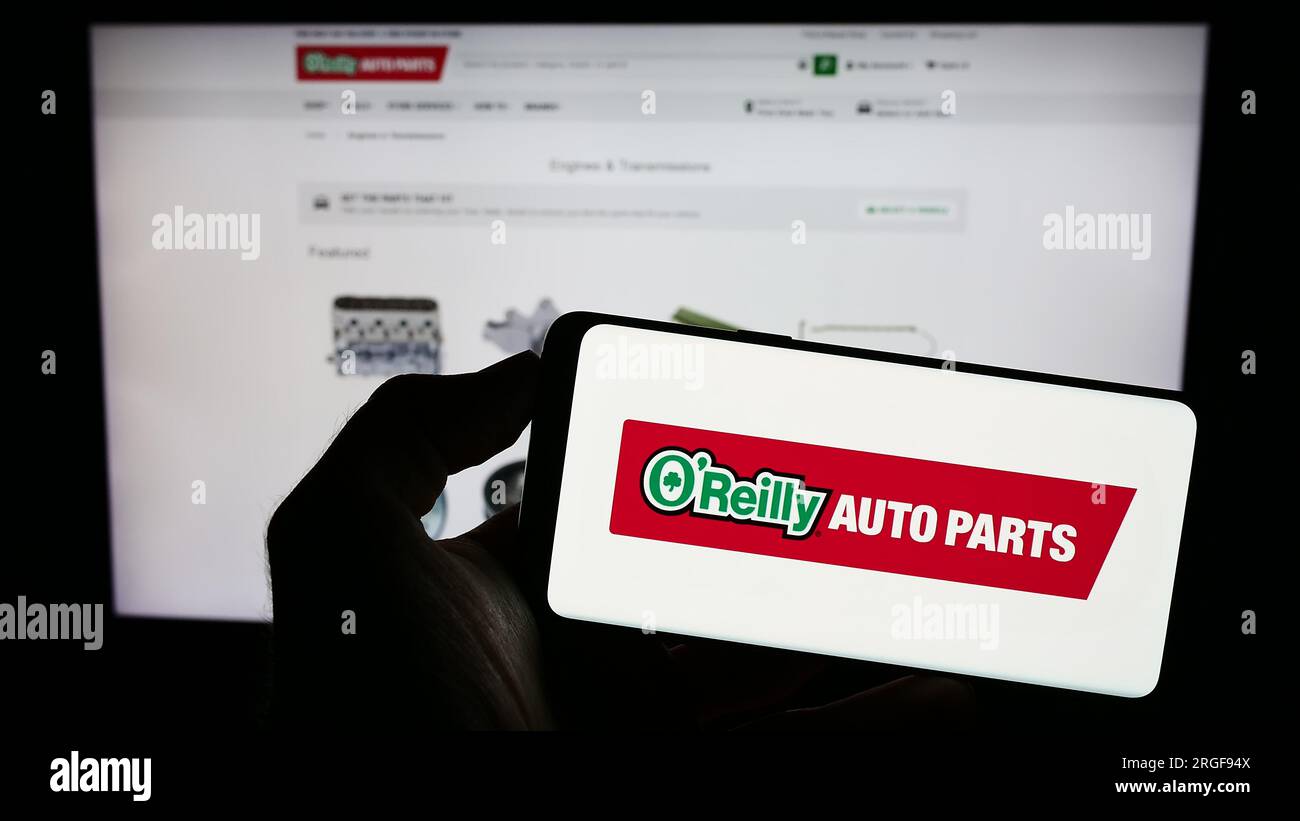 Personne tenant le téléphone portable avec le logo de la société américaine de pièces automobiles O'Reilly Automotive Inc. Sur l'écran en face de la page Web. Concentrez-vous sur l'affichage du téléphone. Banque D'Images