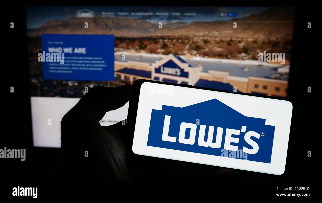 Personne détenant un téléphone intelligent avec le logo de la société de vente au détail américaine Lowe's Companies Inc. Sur l'écran devant le site Web. Concentrez-vous sur l'affichage du téléphone. Banque D'Images