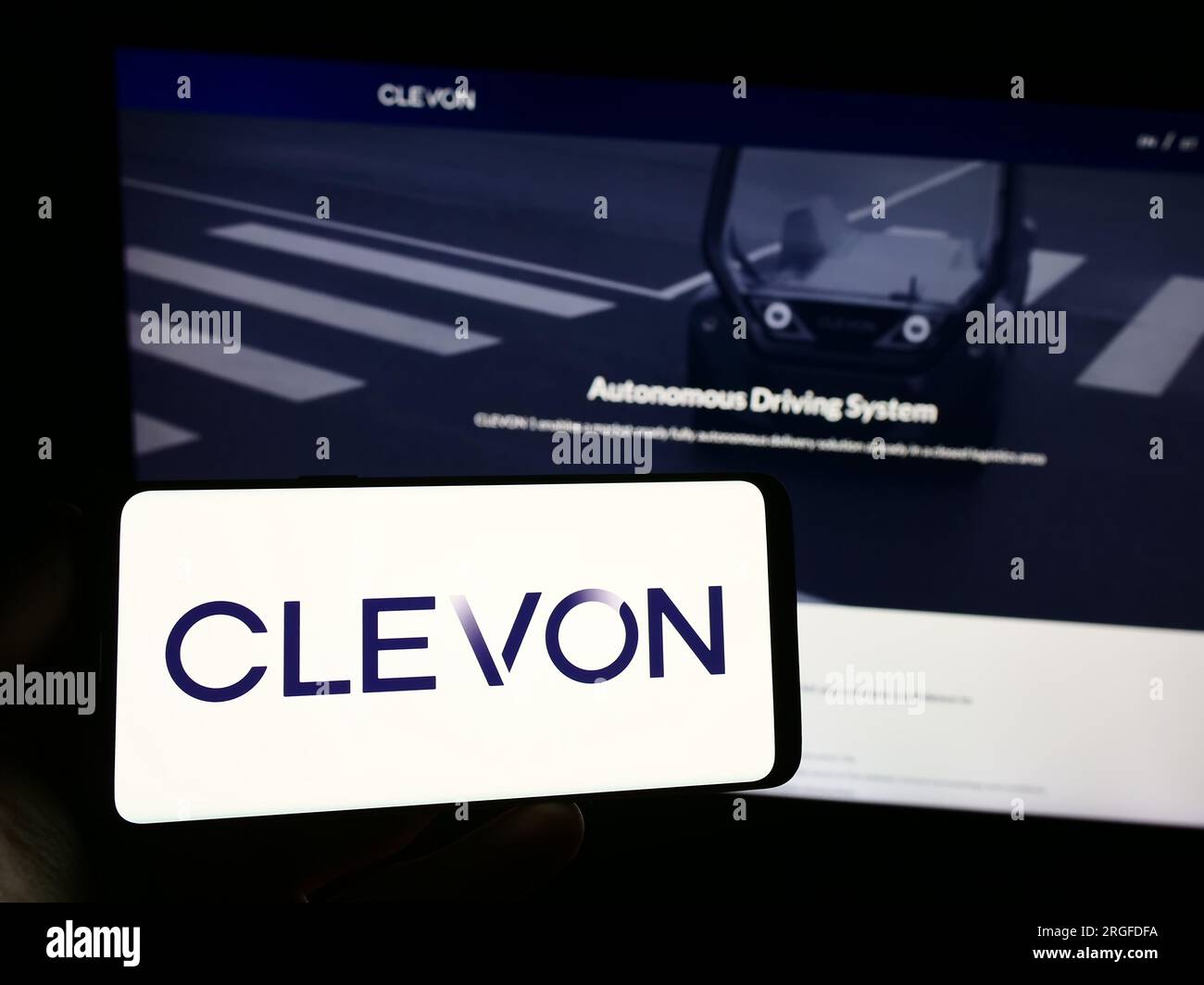 Personne tenant le smartphone avec le logo de la société de véhicules autonomes Estionian Clevon COMME sur l'écran en face du site Web. Concentrez-vous sur l'affichage du téléphone. Banque D'Images
