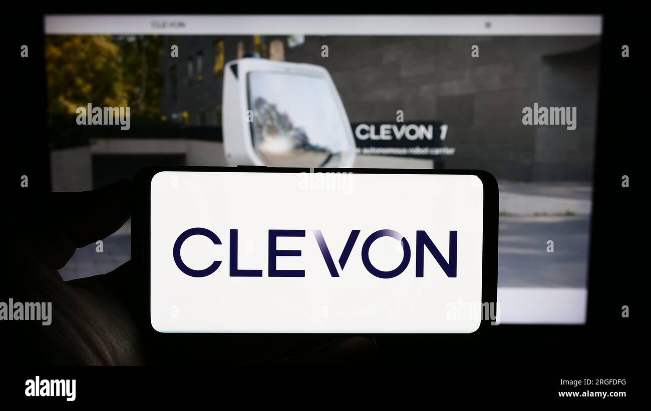 Personne tenant le téléphone mobile avec le logo de la société de véhicule autonome Estionian Clevon COMME sur l'écran en face de la page Web. Concentrez-vous sur l'affichage du téléphone. Banque D'Images
