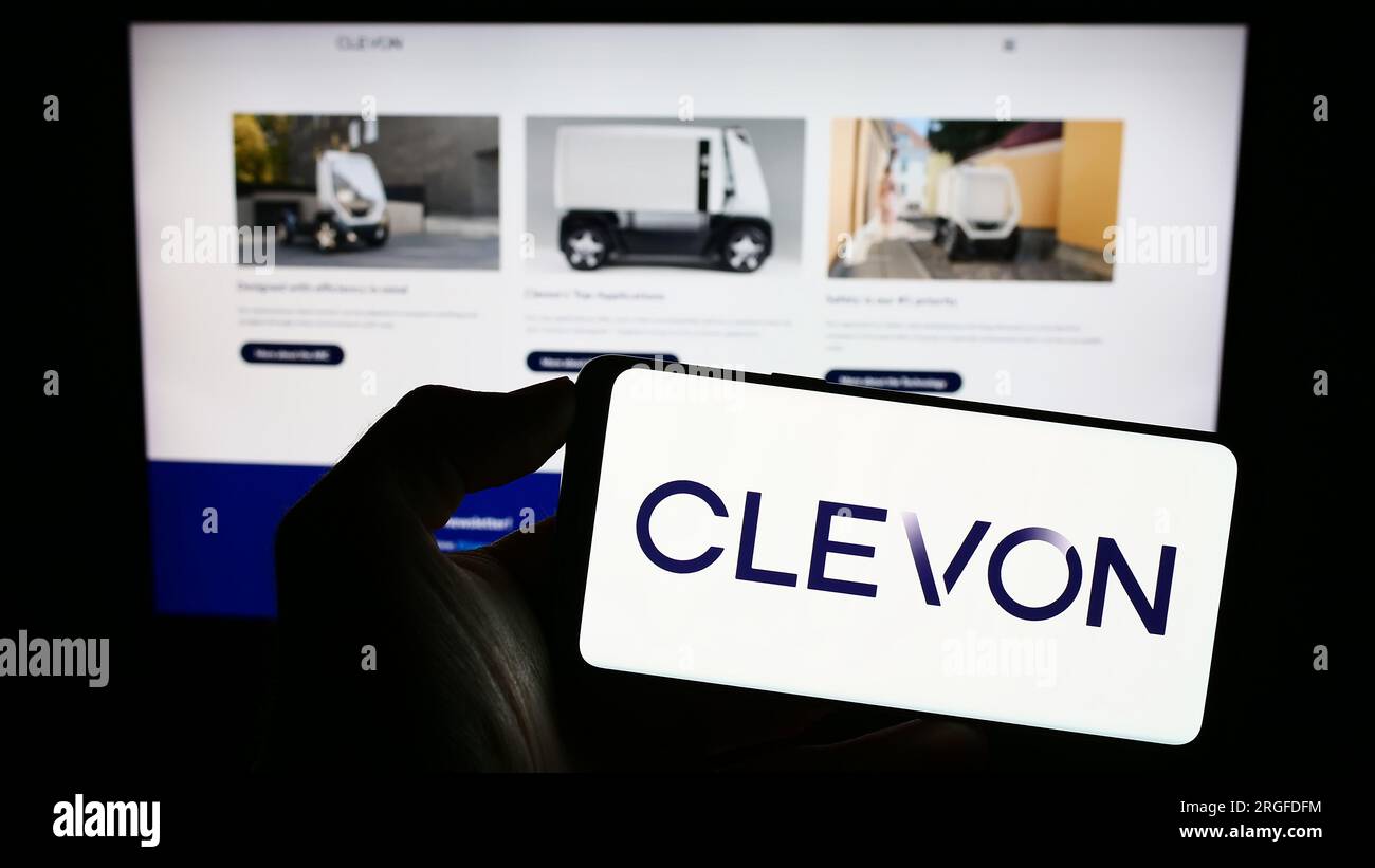 Personne tenant le téléphone portable avec le logo de la société de véhicule autonome Estionian Clevon COMME sur l'écran en face de la page Web. Concentrez-vous sur l'affichage du téléphone. Banque D'Images