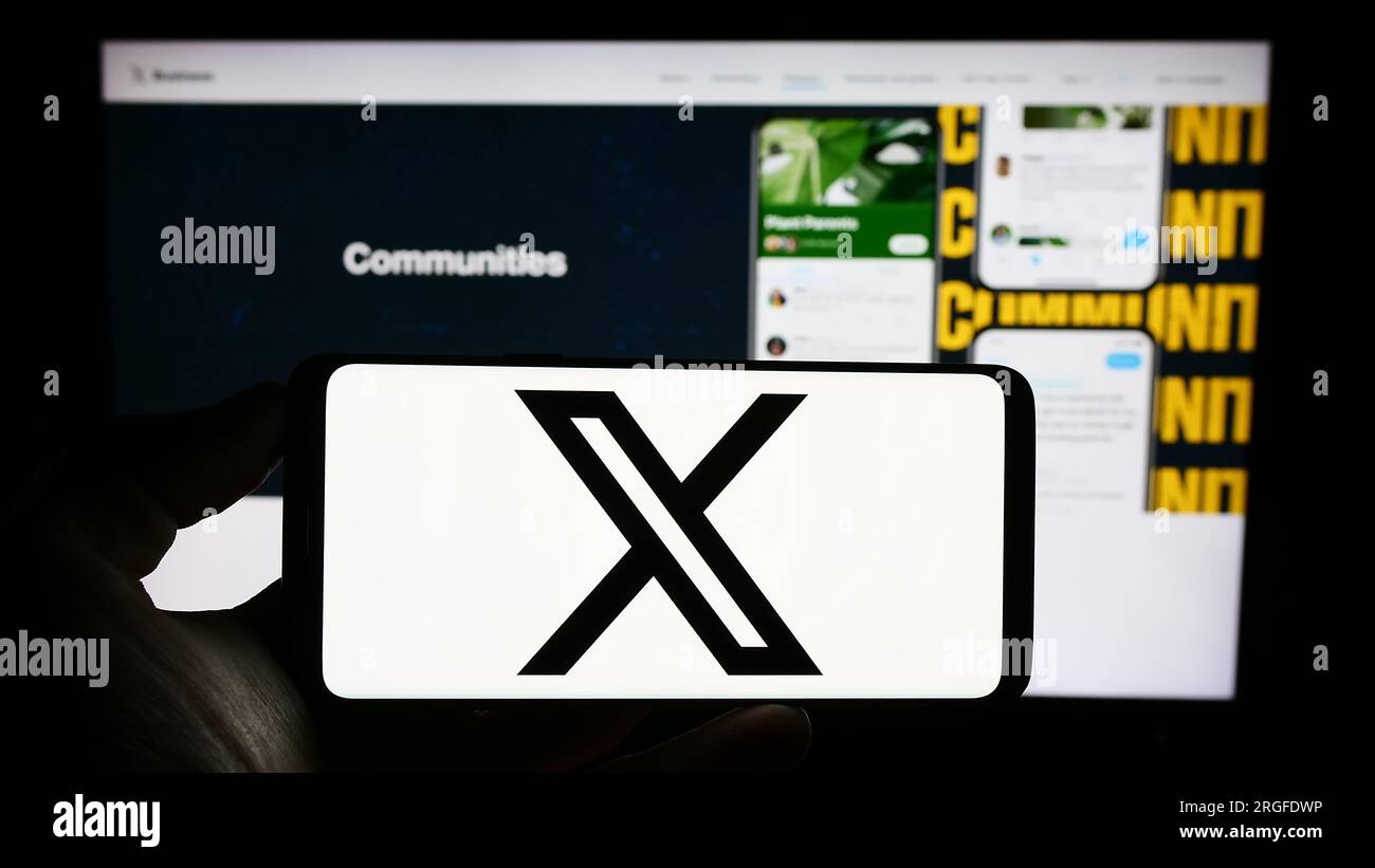 Personne détenant un téléphone portable avec le logo de la société de médias sociaux américaine X Corp. (Twitter) à l'écran devant la page Web de l'entreprise. Concentrez-vous sur l'affichage du téléphone. Banque D'Images
