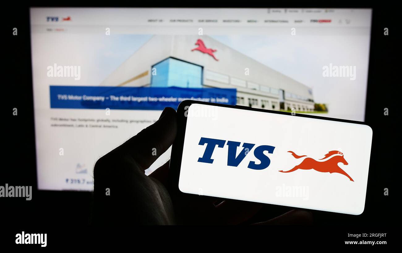 Personne tenant un smartphone avec le logo de la société de motos TVS Motor Company Limited sur l'écran devant le site Web. Concentrez-vous sur l'affichage du téléphone. Banque D'Images