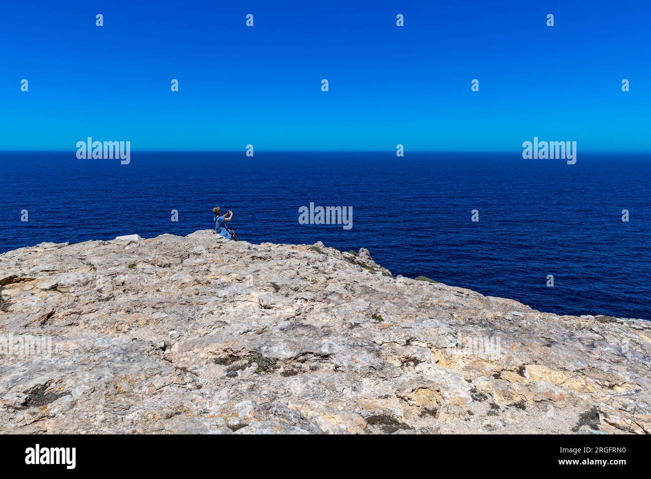 femme sur le bord de mer rocheux prend la photo avec smartphone Banque D'Images