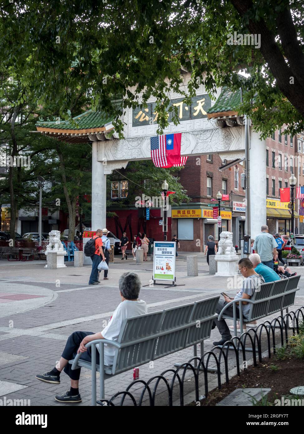 Boston, Massachusetts, États-Unis - Chinatown Gate avec les drapeaux américain et taïwanais accrochés ensemble. Des vieillards reposant sur un banc. Banque D'Images