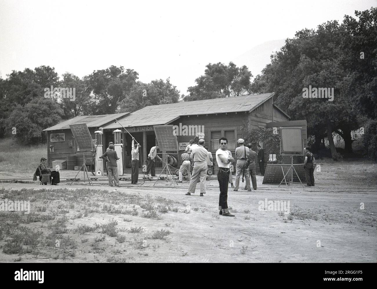 Années 1950, historique, un film hollywoodien ou un décor de film, montrant des paysages spécialement construits d'une petite station d'essence rurale. Des techniciens de cinéma et d'éclairage, des caméramans et d'autres professionnels du cinéma se tiennent autour du plateau, Los Angeles, Californie, États-Unis Banque D'Images