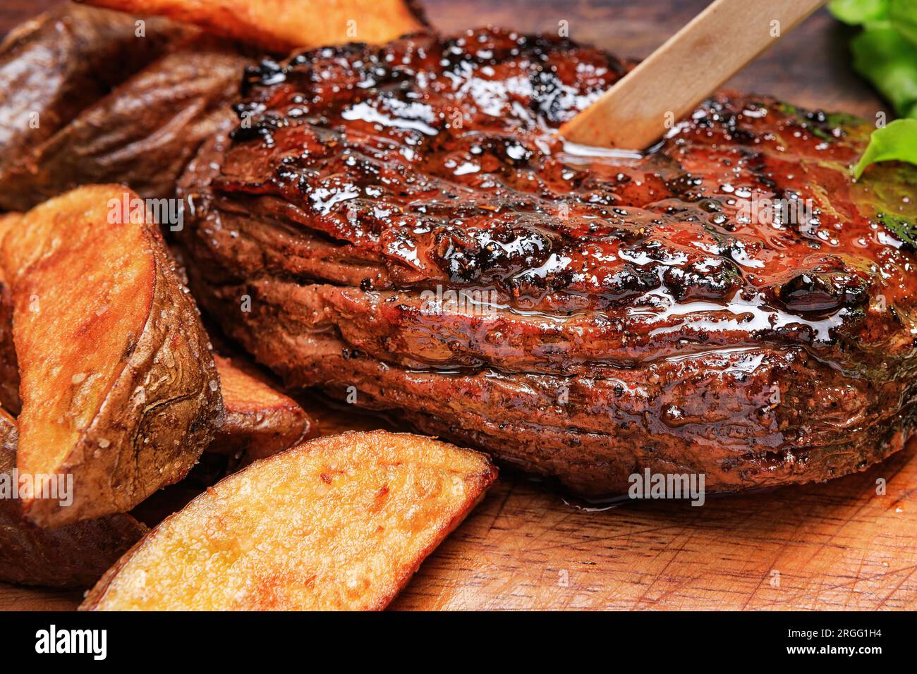 Steak de bœuf avec frites et laitue sur une planche de bois Banque D'Images