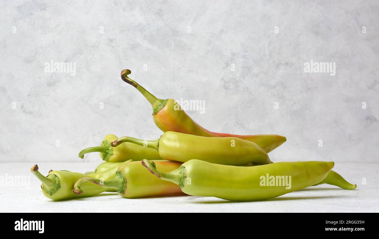 pile de poivrons banane sur le dessus de table blanc, capsicum annuum, piment long, forme incurvée avec une chaleur douce et une saveur acidulée et légèrement sucrée Banque D'Images