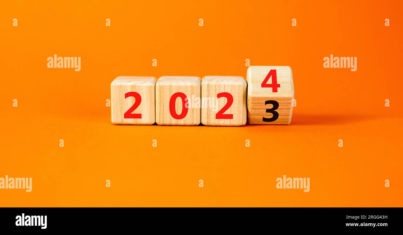 symbole de bonne année 2024. Cubes en bois avec numéro 2023 et 2024. Belle table orange fond orange, espace de copie. Business et 2024 heureux nouveau Banque D'Images