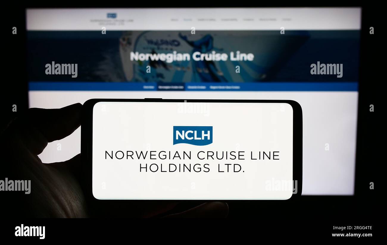 Personne tenant un téléphone portable avec le logo de la société Norwegian Cruise Line Holdings Ltd. Sur l'écran devant la page Web de l'entreprise. Concentrez-vous sur l'affichage du téléphone. Banque D'Images