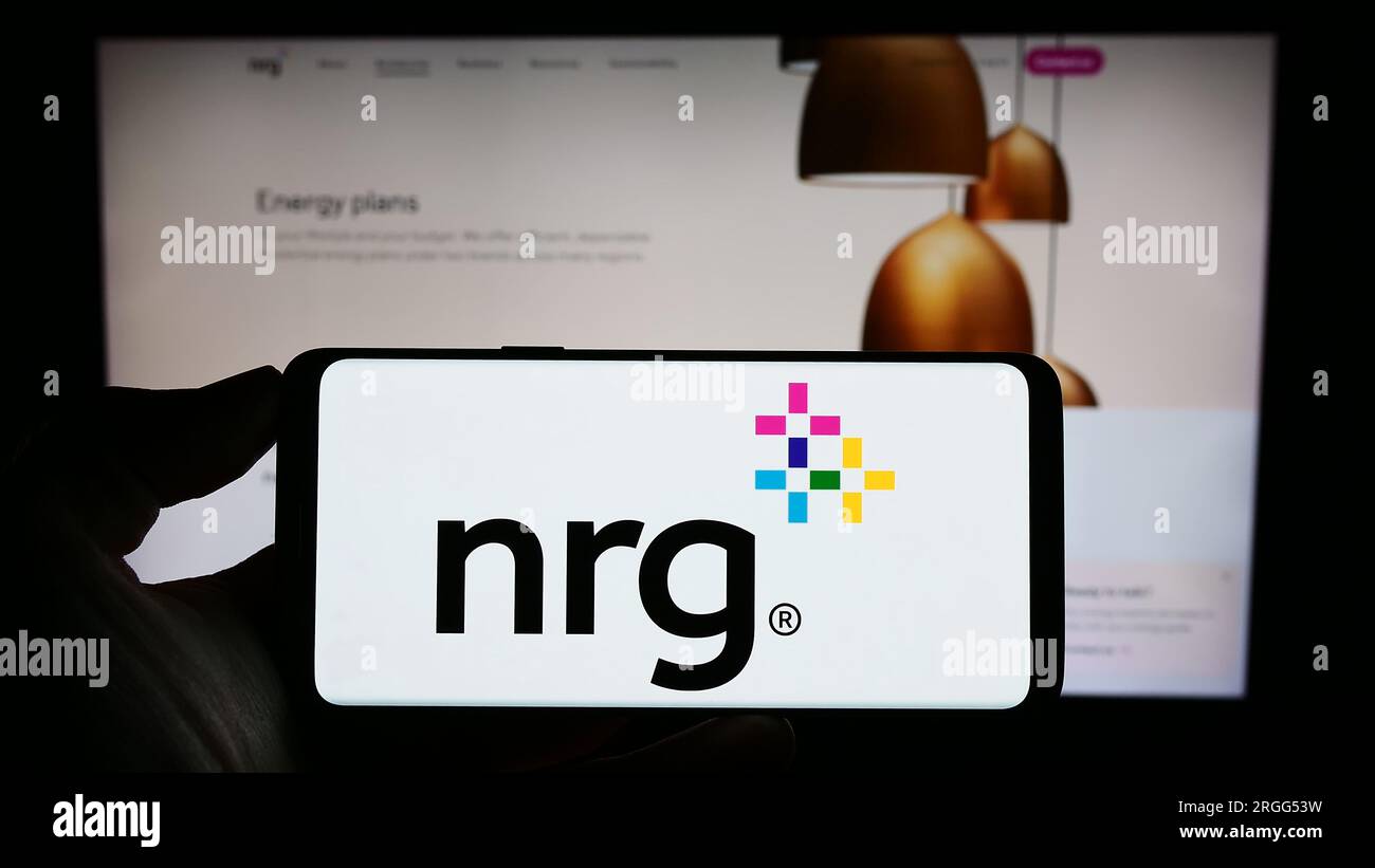 Personne tenant le téléphone cellulaire avec le logo de la compagnie de services publics américaine NRG Energy Inc. Sur l'écran devant la page Web de l'entreprise. Concentrez-vous sur l'affichage du téléphone. Banque D'Images