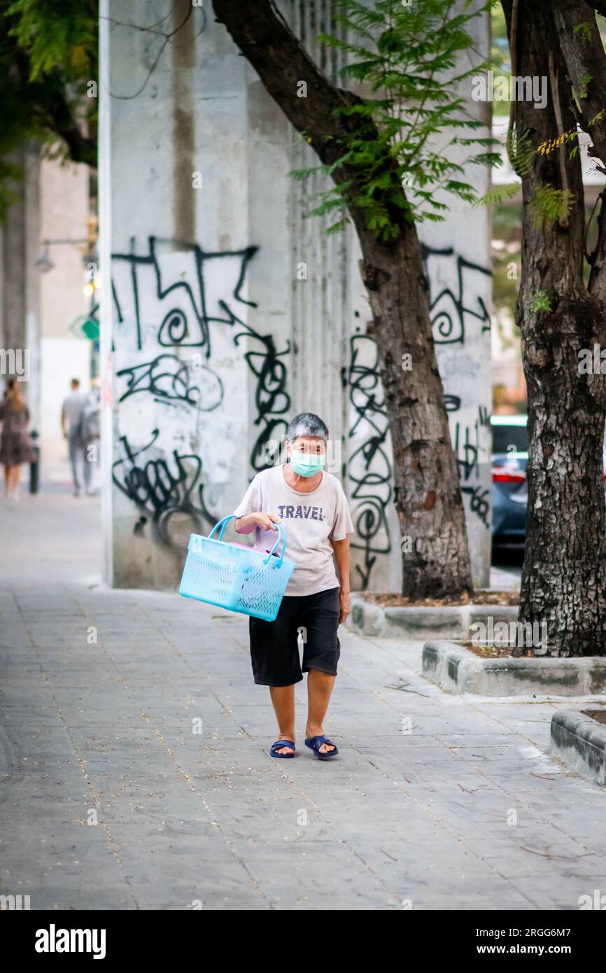 Une vieille dame thaïlandaise fait son chemin le long de Chong Nonsi portant son sac à provisions. Banque D'Images
