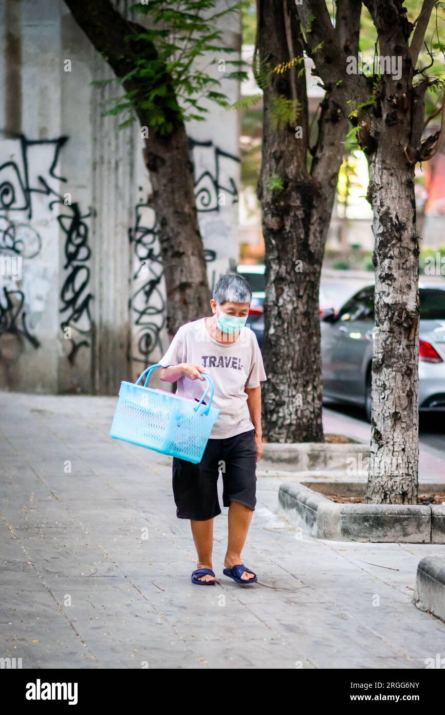 Une vieille dame thaïlandaise fait son chemin le long de Chong Nonsi portant son sac à provisions. Banque D'Images