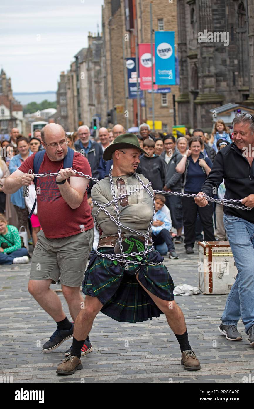 Centre-ville, Édimbourg, Écosse, Royaume-Uni. 9 août 2023. Au milieu de la première semaine du Festival d'Édimbourg Fringe with Street Performers fait le tour de la ville, avec un grand public sur deux emplacements sur High Street, Royal Mile, en photo : Eddie Bond se fait envelopper de chaînes pour s'échapper de la routine des vestes Straight. Crédit : Archwhite/alamy Live News. Banque D'Images