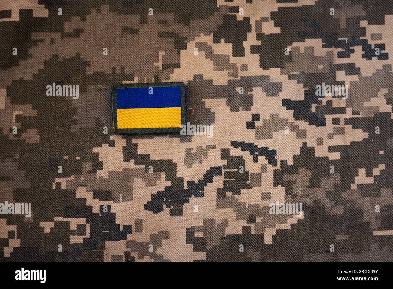 Photo de la bannière du drapeau ukrainien sur le textile de camouflage avec des couleurs de pixel militaire. Banque D'Images