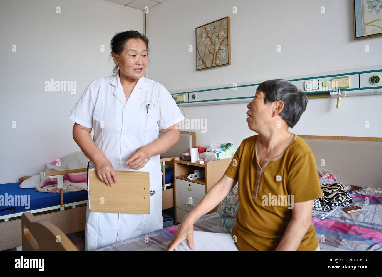 Tianjin, Chine. 9 août 2023. Un travailleur médical enseigne alors qu’une femme âgée apprend l’utilisation de la médecine sur un site de relocalisation à Tianjin, dans le nord de la Chine, le 9 août 2023. Le district de Jinghai à Tianjin, dans le nord de la Chine, a fait des efforts pour protéger la vie de plus de 2 000 habitants touchés par les inondations après la mise en service d'une zone de rétention et de rétention des eaux de crue. Crédit : Li Ran/Xinhua/Alamy Live News Banque D'Images