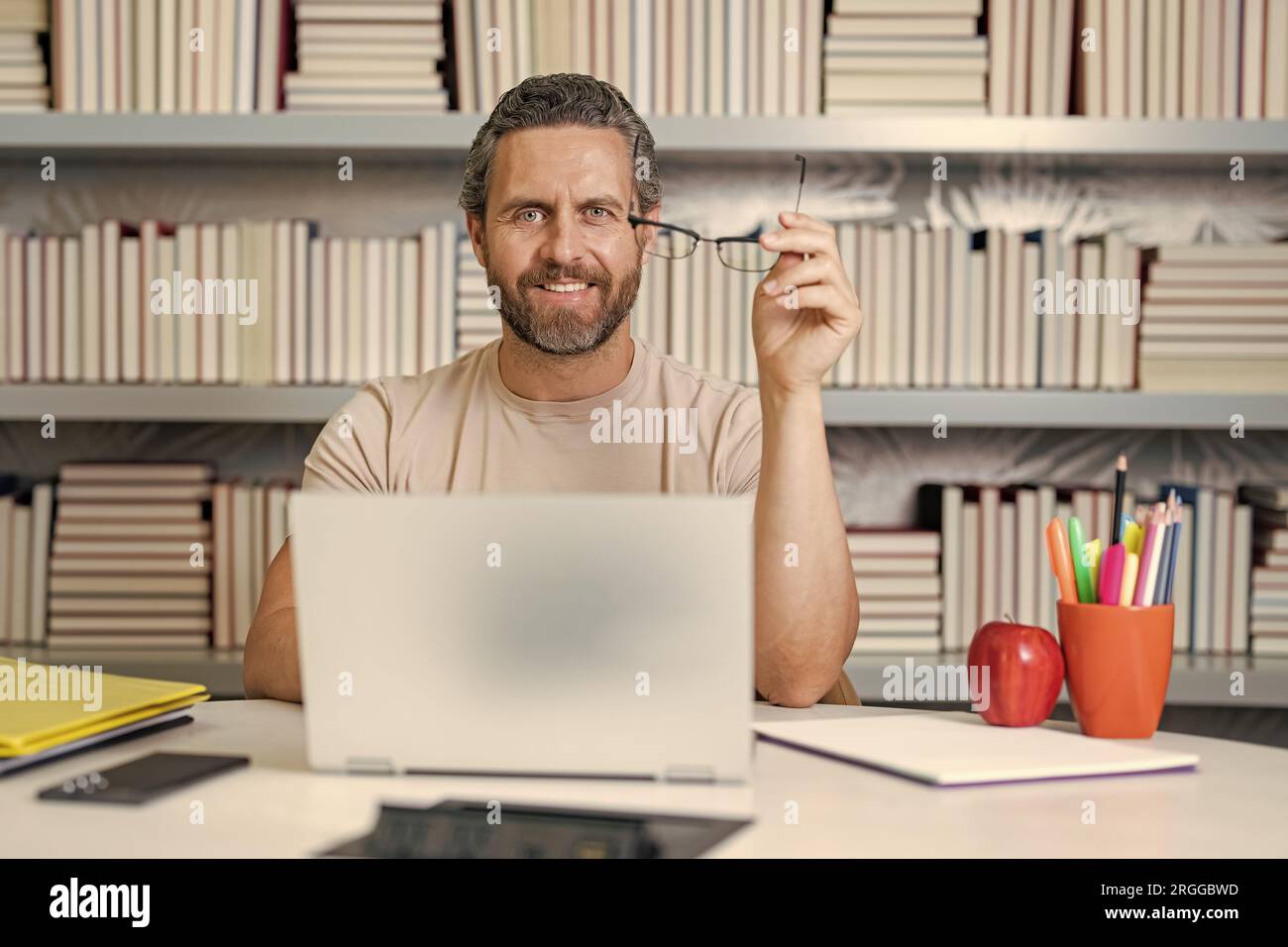 Journée des enseignants. Bon professeur avec un ordinateur portable dans la salle de classe. Connaissance et éducation avec un enseignant d'âge moyen. Professeur hispanique avec livre. Enseignant Banque D'Images