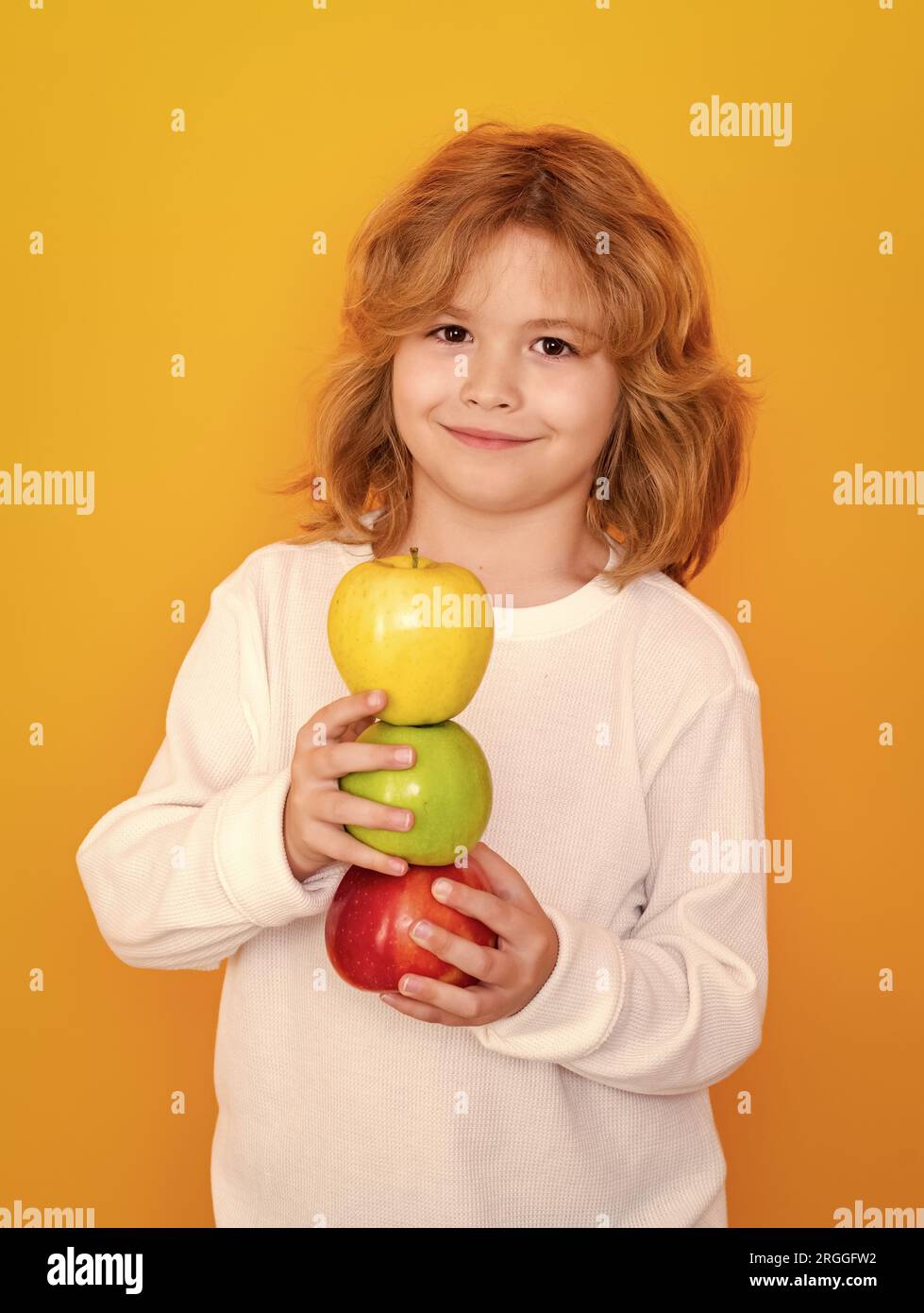 Vitamines et fruits sains pour les enfants. Enfant avec pomme en studio. Portrait de studio de l'enfant mignon tenir la pomme isolée sur fond jaune Banque D'Images