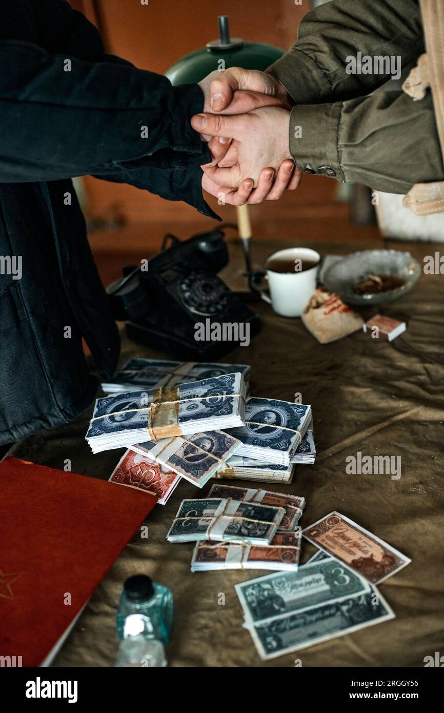 De l'argent sur la table et une poignée de main des hommes à une faible profondeur de champ Banque D'Images