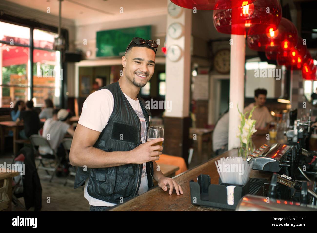 Homme souriant au bar avec un verre Banque D'Images