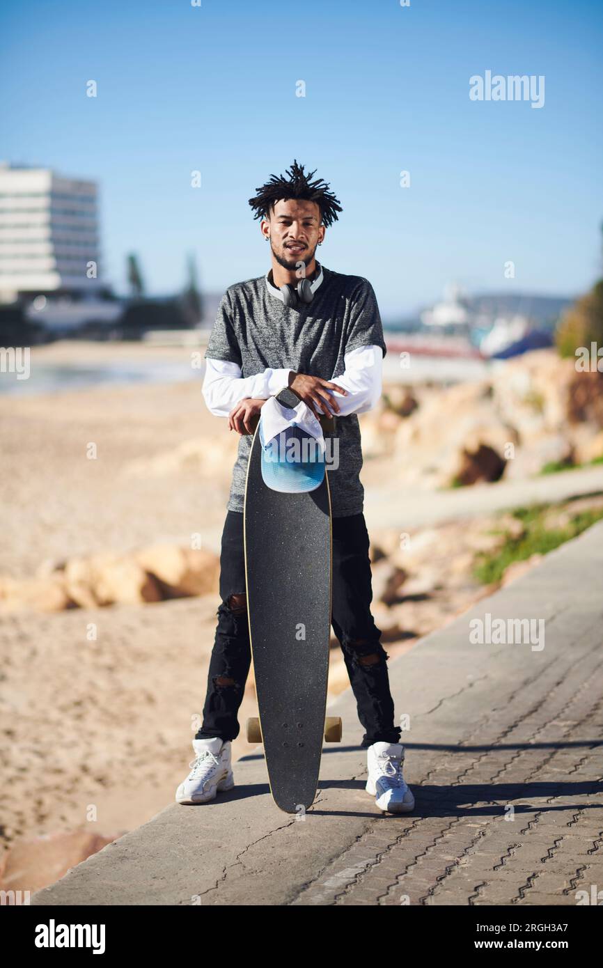 Young man leaning on skateboard Banque D'Images