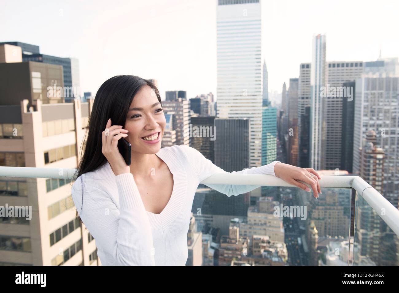 Jeune femme à l'aide du smartphone sur le balcon à New York City Banque D'Images