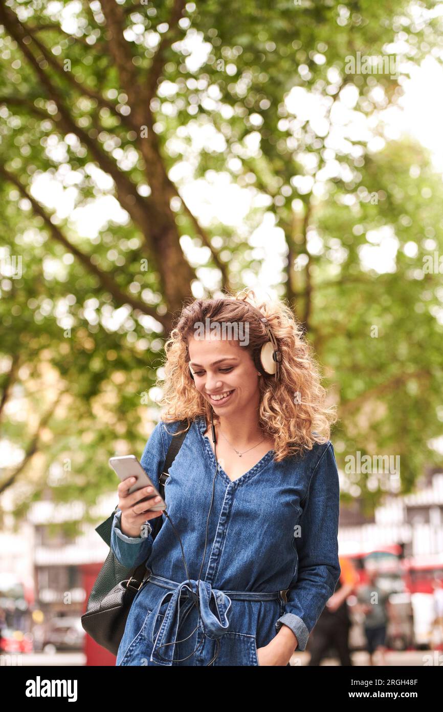 Young woman holding smart phone wearing headphones Banque D'Images