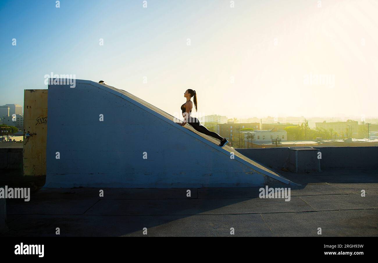 Jeune femme qui s'étend sur une rampe sur le toit Banque D'Images