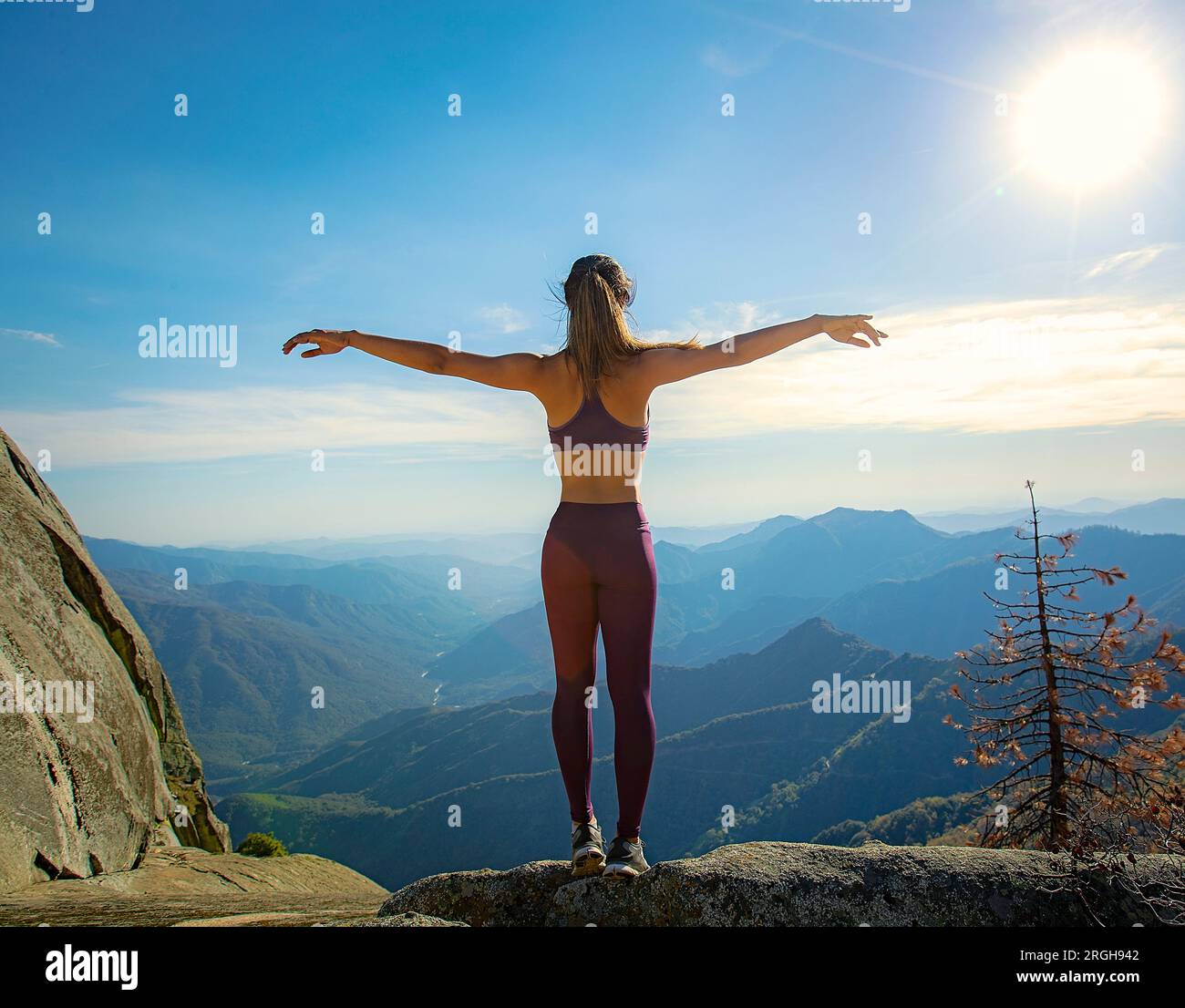 Young woman with arms outstretched on mountain Banque D'Images