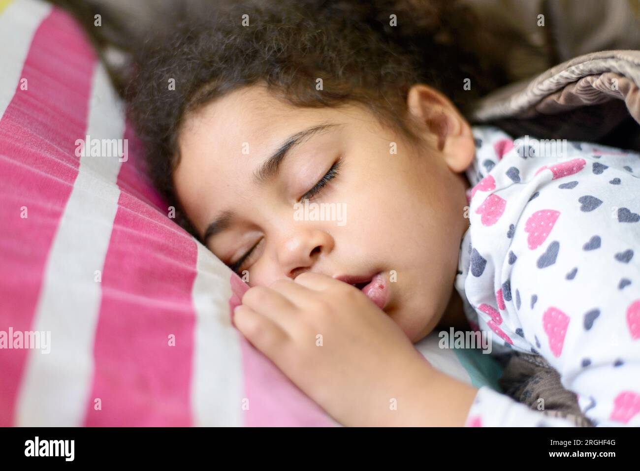 Enfant noir dormant dans la chambre. Jeune fille fatiguée faisant une sieste et se reposant, se brisant et un développement sain de l'enfance Banque D'Images