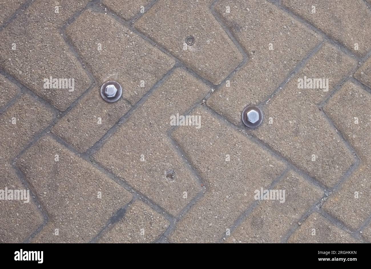 Deux têtes de boulon d'arpenteur sur un trottoir avec des briques à motifs à Madrid Espagne Banque D'Images