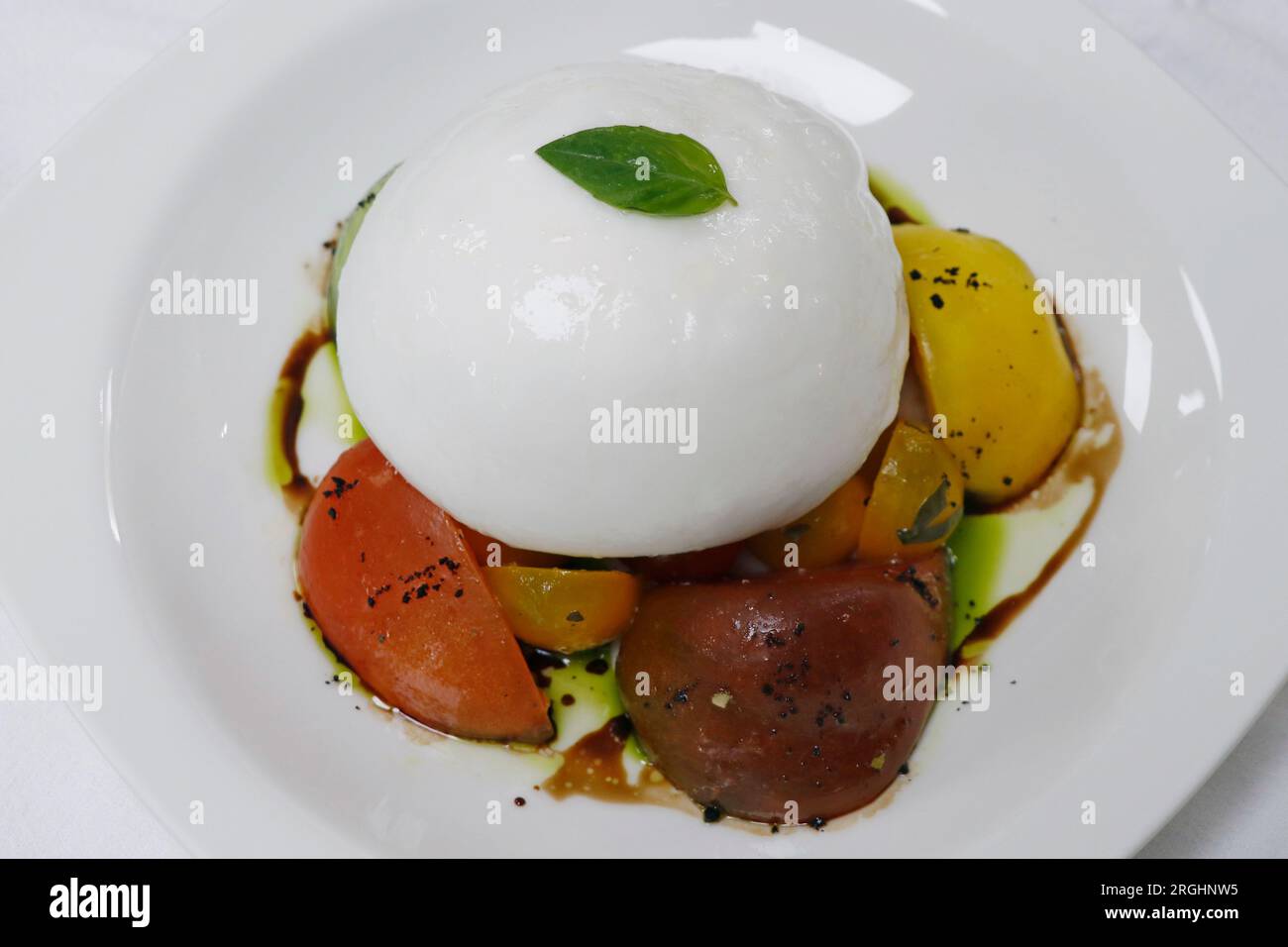 mozzarella de buffle italienne ou burrata avec salade de tomates sur une assiette blanche Banque D'Images