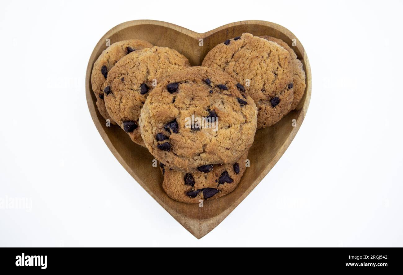 Biscuits aux pépites de chocolat sur une assiette en forme de coeur sur un fond blanc Banque D'Images