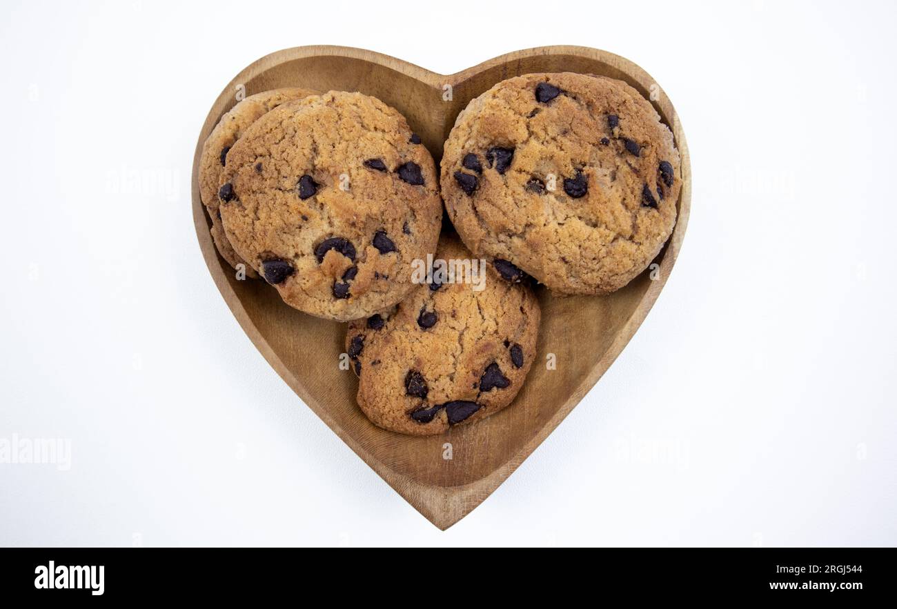 Biscuits aux pépites de chocolat sur une assiette en forme de coeur sur un fond blanc Banque D'Images