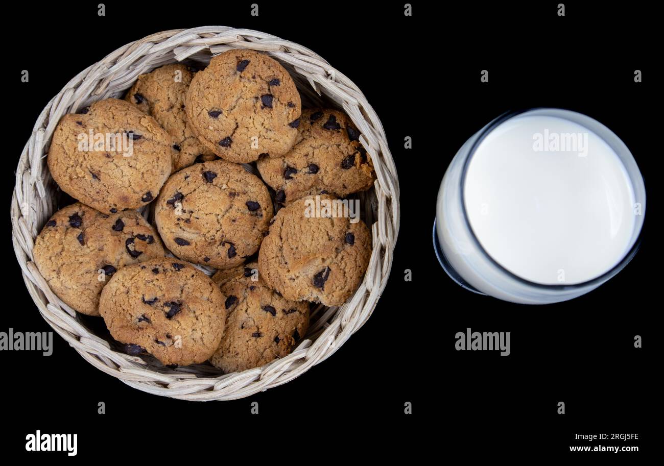 Biscuits au lait frais et aux pépites de chocolat dans un panier en bambou isolé sur fond noir Banque D'Images