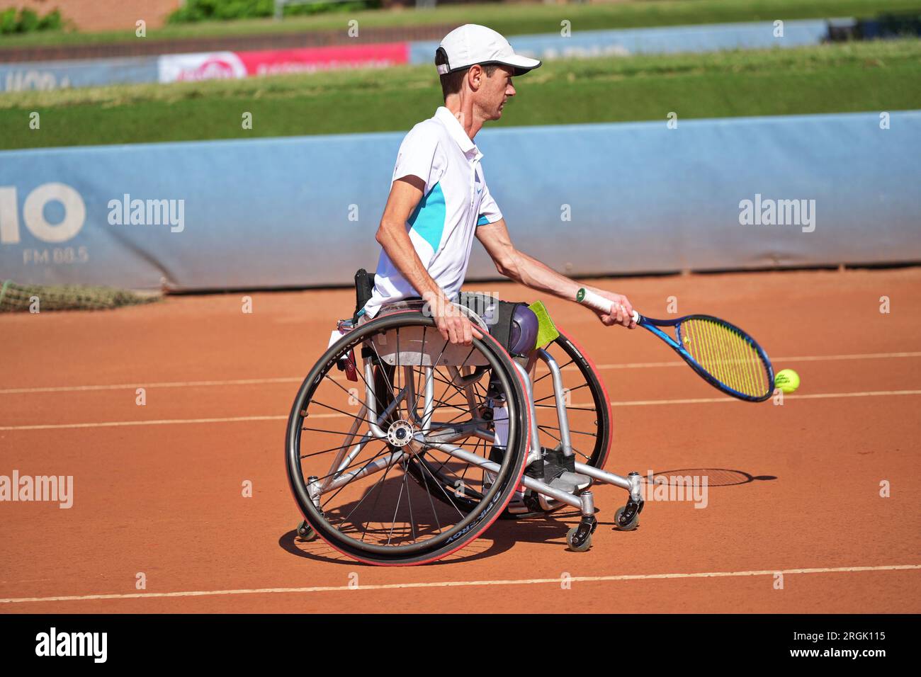 Homme pratique le tennis en fauteuil roulant sur un court de terre battue. Tennis en fauteuil roulant. Banque D'Images