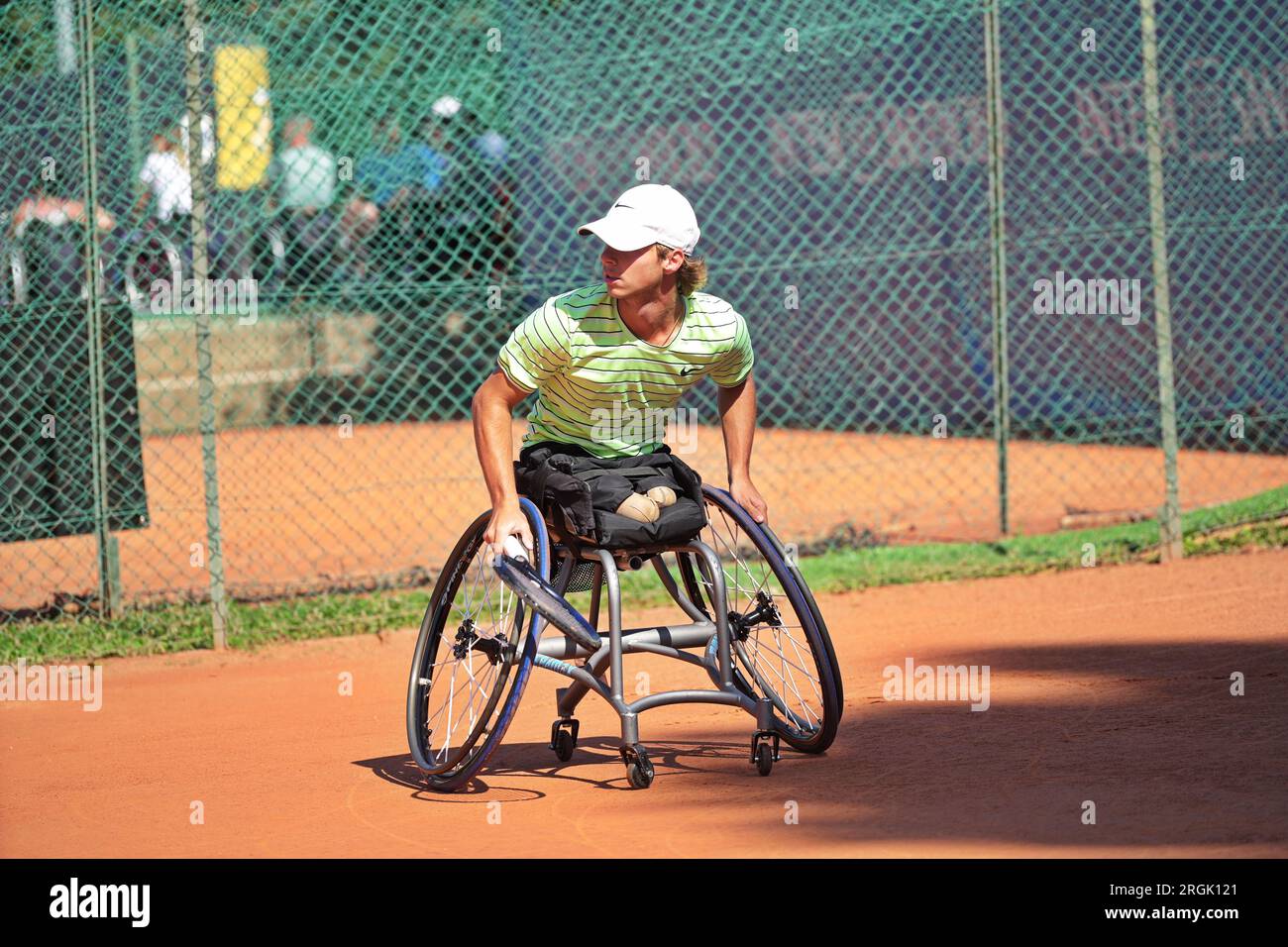 Homme pratique le tennis en fauteuil roulant sur un court de terre battue. Tennis en fauteuil roulant. Banque D'Images