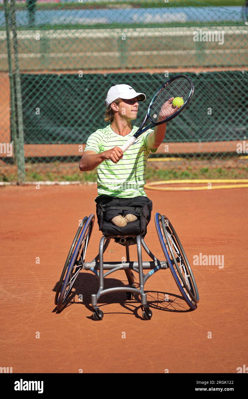 Homme pratique le tennis en fauteuil roulant sur un court de terre battue. Tennis en fauteuil roulant. Banque D'Images