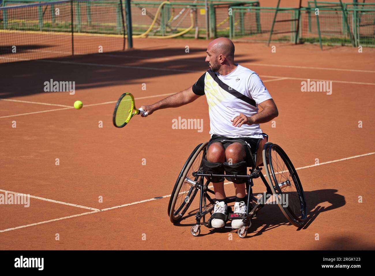 Homme pratique le tennis en fauteuil roulant sur un court de terre battue. Tennis en fauteuil roulant. Banque D'Images