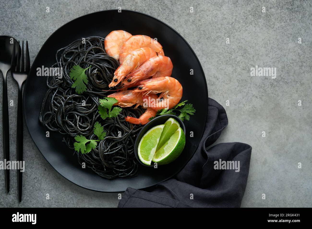Crevettes noires de pâtes spaghetti sur plaque noire sur fond de table en béton foncé. Pâtes à l'encre de calmar aux crevettes. Pâtes et fruits de mer. Vue de dessus sur l'onglet de pierre grise Banque D'Images