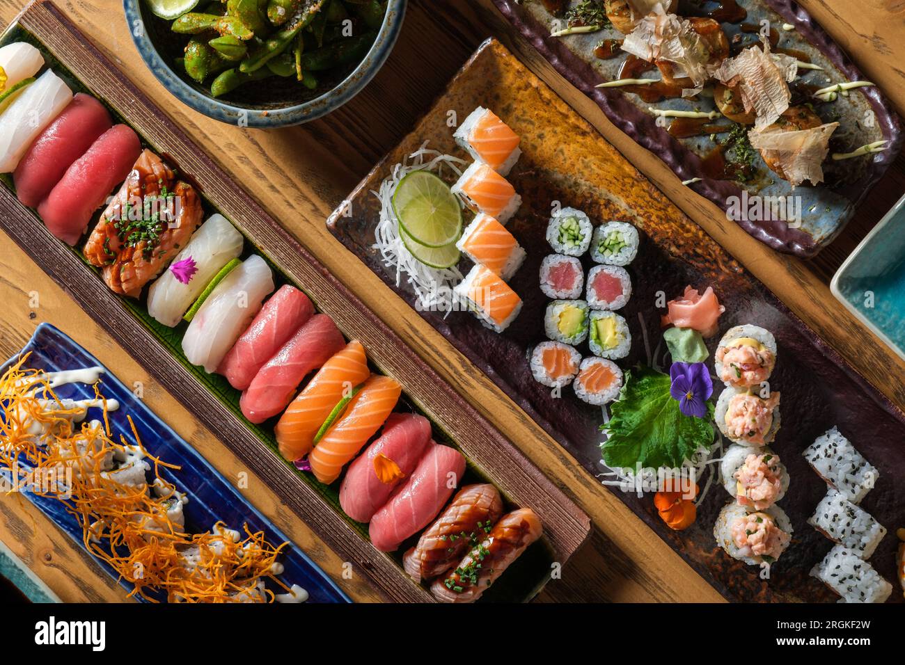 Vue de dessus de divers sushis frais et rouleaux avec différents poissons servis sur des plateaux en bois avec des crevettes dans un café léger Banque D'Images