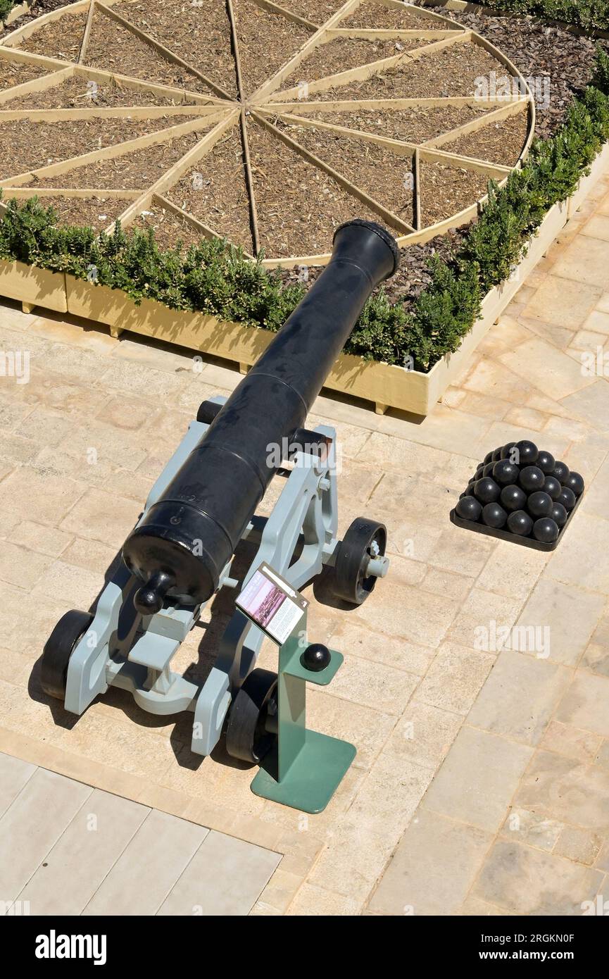 La Valette, Malte - 8 juin 2023 : vue regardant vers le bas un vieux canon sur les fortifications de la ville, à côté d'un tas de répliques de boulets de canon. Banque D'Images