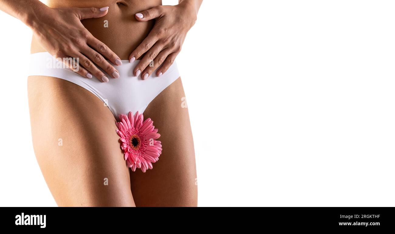 Beau corps féminin avec un gerbera rose à l'entrejambe. Une femme a une fleur dans son ventre symbolisant le cycle menstruel ou l'hygiène. Isolé sur whit Banque D'Images