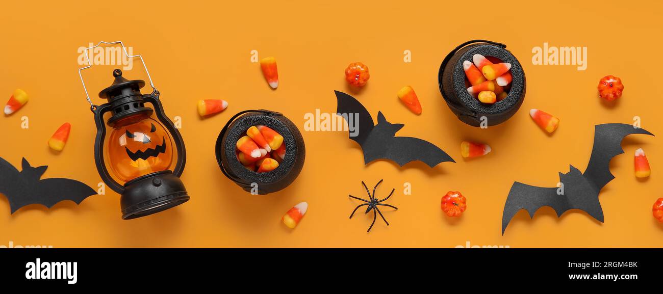 Composition avec des cors de bonbons savoureux, lanterne et décor d'Halloween sur fond orange, vue de dessus Banque D'Images