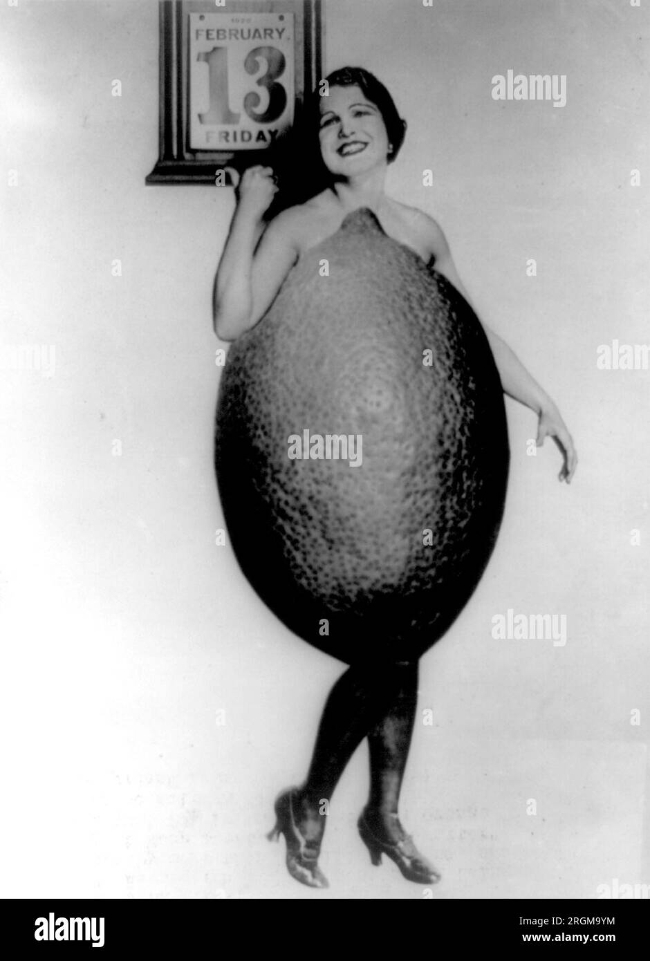 Miss Rose Cade--Reine des citrons - Rose Cade, qui a également été nommée fille du sud de la Californie 'Swat the Jinx', habillée en modèle de grand citron pointant vers le calendrier daté vendredi 13 février 1920 ca. 1920 Banque D'Images