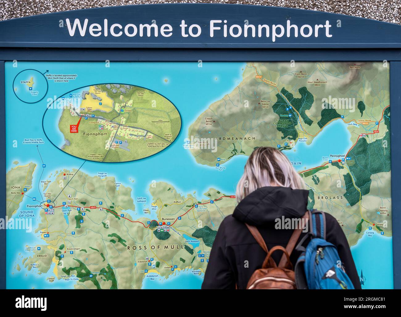 Touriste féminine regardant une grande carte sur un mur à Fionnphort sur l'île de Mull, en Écosse, où les ferries font le court voyage à l'île d'Iona Banque D'Images