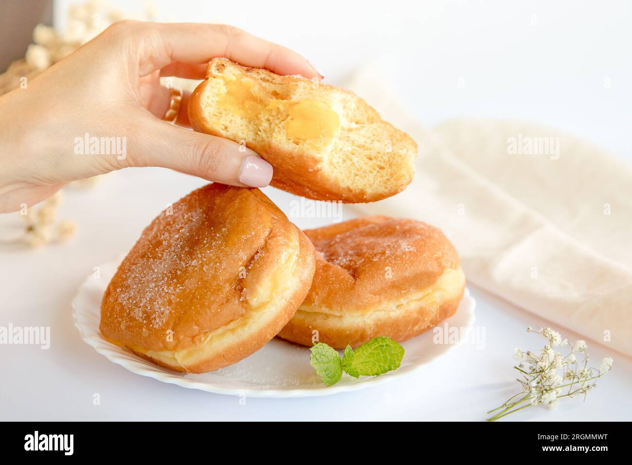 Bolas de Berlim, Berliner ou beignets farcis à la confiture d’œufs, un dessert très populaire dans les pâtisseries portugaises. Personne goûtant un bal de berlin. Banque D'Images